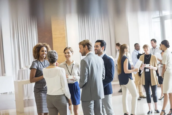 Executivos em audit&oacute;rio. em p&eacute;, exercitando o que aprenderam sobre comunica&ccedil;&atilde;o efetiva. 