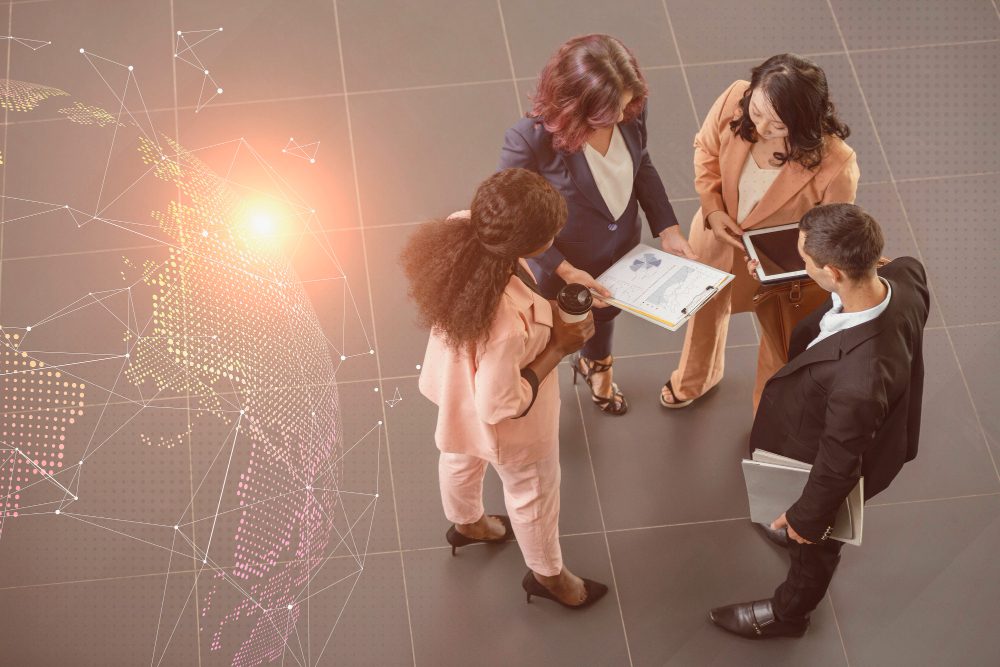 Grupo de profissionais discutindo estratégias de tecnologia e inovação em um ambiente corporativo, com gráficos e dispositivos eletrônicos.